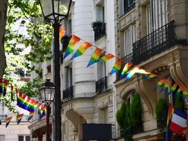 Décoration composée de banderoles triangulaires aux couleurs des drapeaux LGBTQ, suspendues aux balcons. Paris, France.